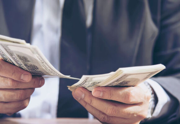 Image of a wealthy person holding many 100 dollar bills