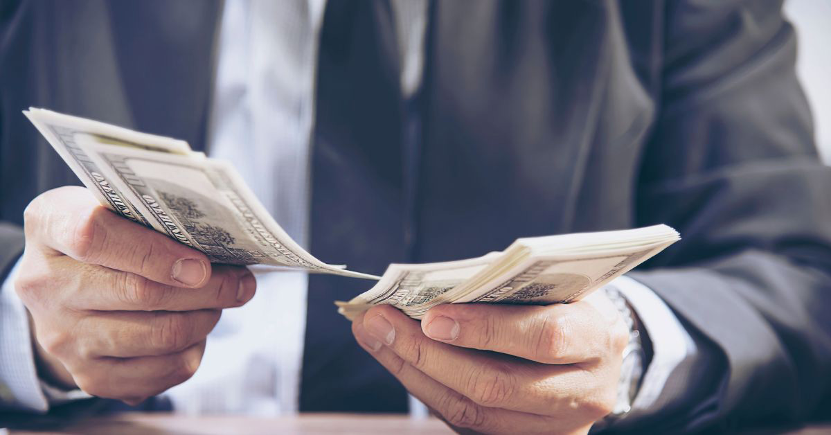 Image of a wealthy person holding many 100 dollar bills