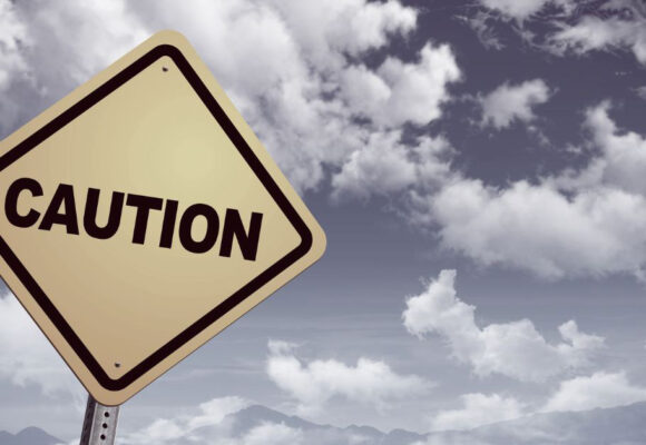 Image of a caution sign against a cloudy sky
