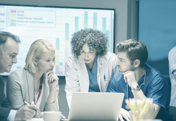 Image of doctors and healthcare admins looking at a laptop