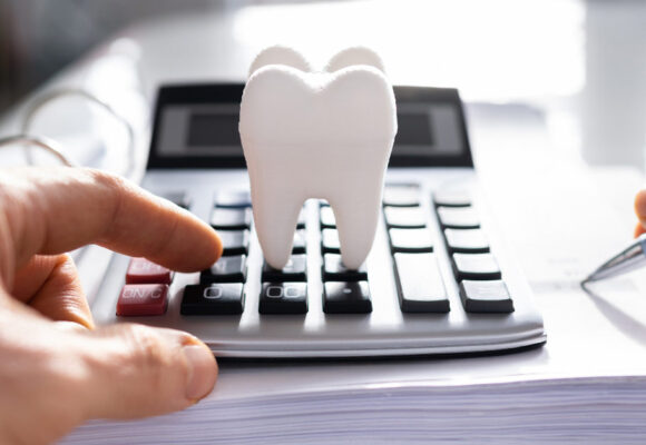 Image of a desk with a calculator on it, with a tooth perched
