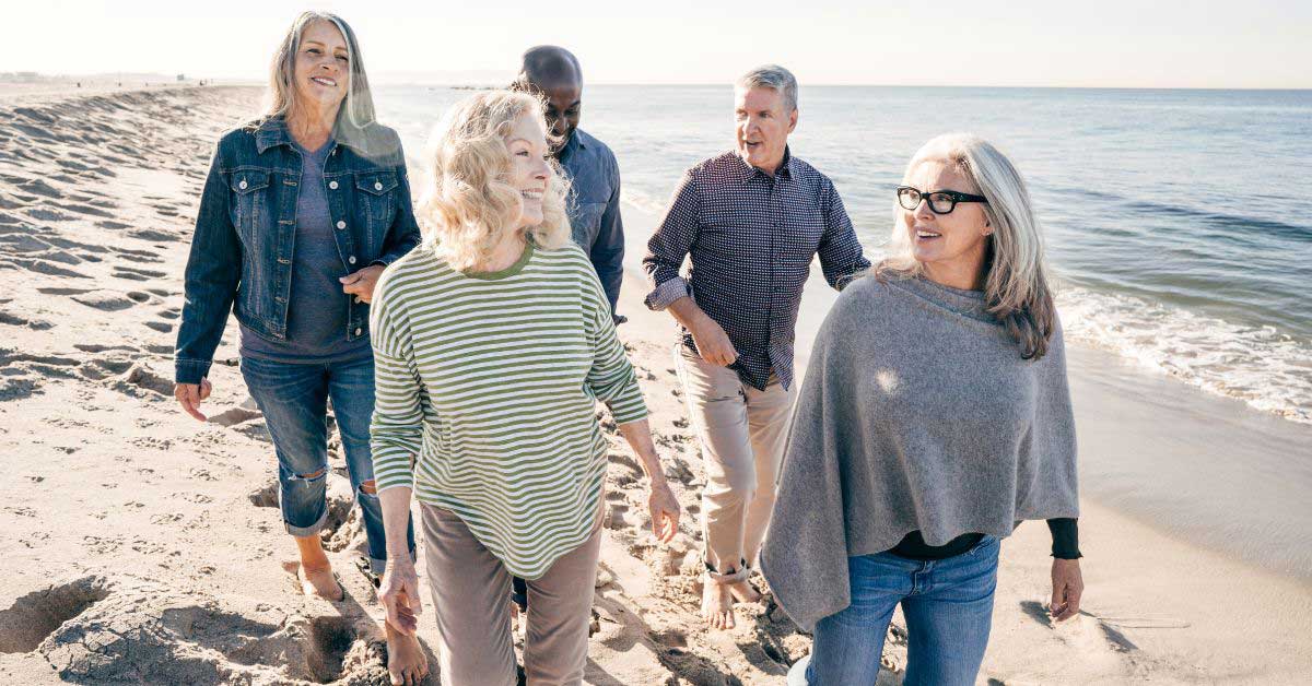 Image of retired couples happily walking on the beach