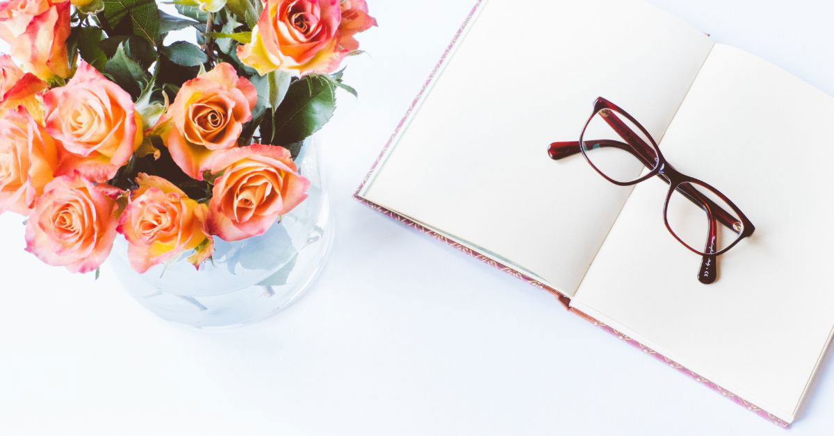 Image of a blank notebook with glasses on it, plus a bouquet of flowers
