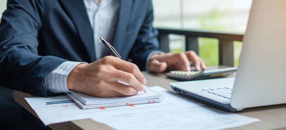 Photo of practice administrator calculating physician compensation strategies with paper and calculator