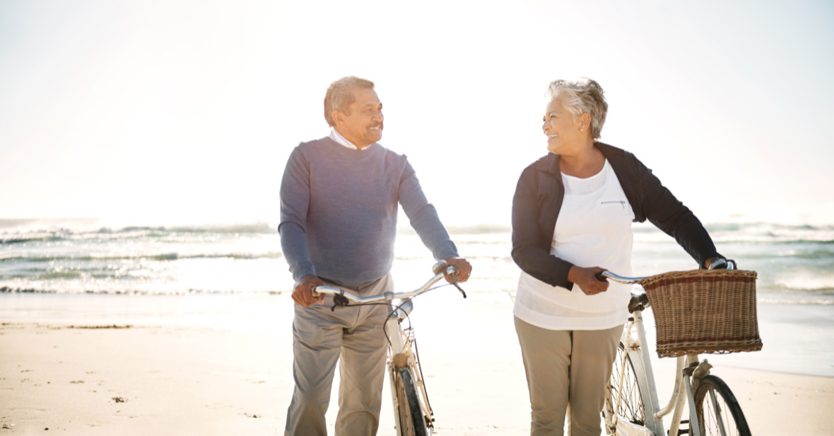 Image of retired couple with bicycles on the beach