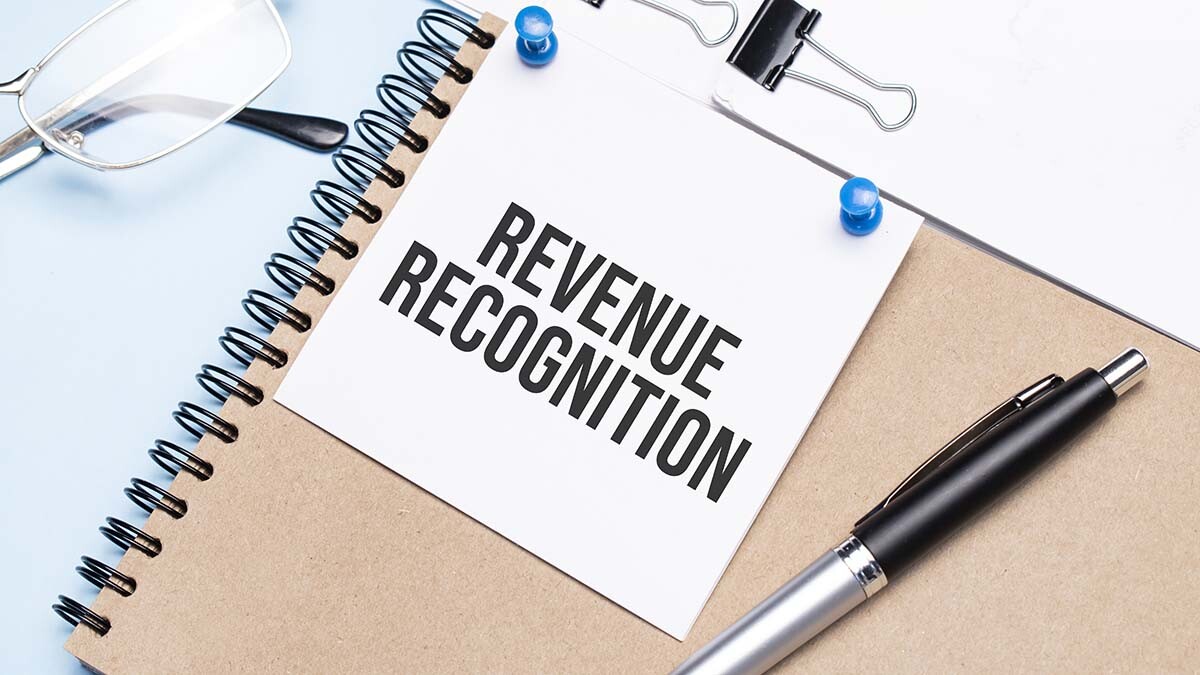 Image of a notebook and a sign that says 'Revenue Recognition'
